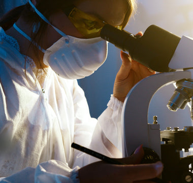 Woman in Lab Looking Through Microscope